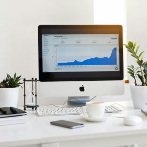 pexels-photo-572056-572056 A clean, contemporary workspace featuring a desktop with analytics on the screen and plants for a fresh look.
