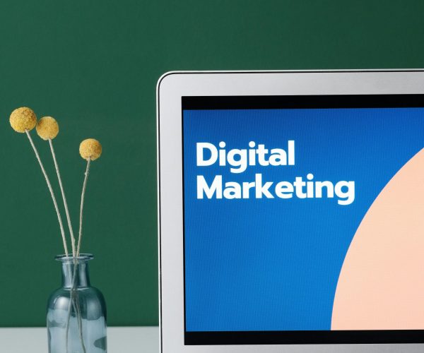 pexels-photo-6483583-6483583 A laptop displaying 'Digital Marketing' with a minimalist floral decor in a glass vase.